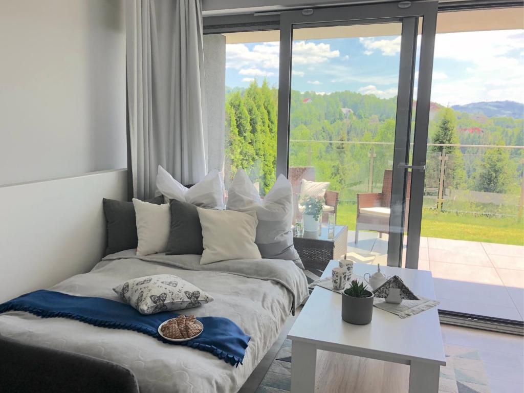 a bed in a room with a large window at Apartament Na Bukowej - Wisła, widokowe studio in Wisła