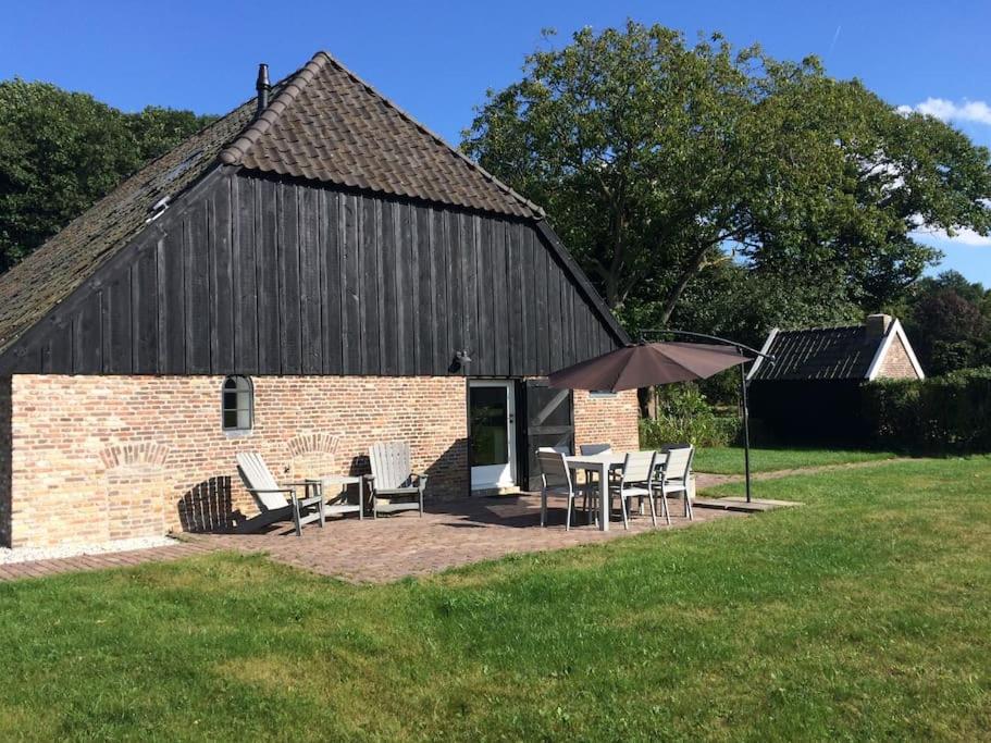 a barn with a table and chairs and an umbrella at Ottenstein in Hierden