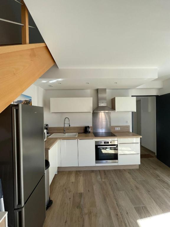 a kitchen with white cabinets and a stainless steel refrigerator at Duplex en plein centre in Propriano