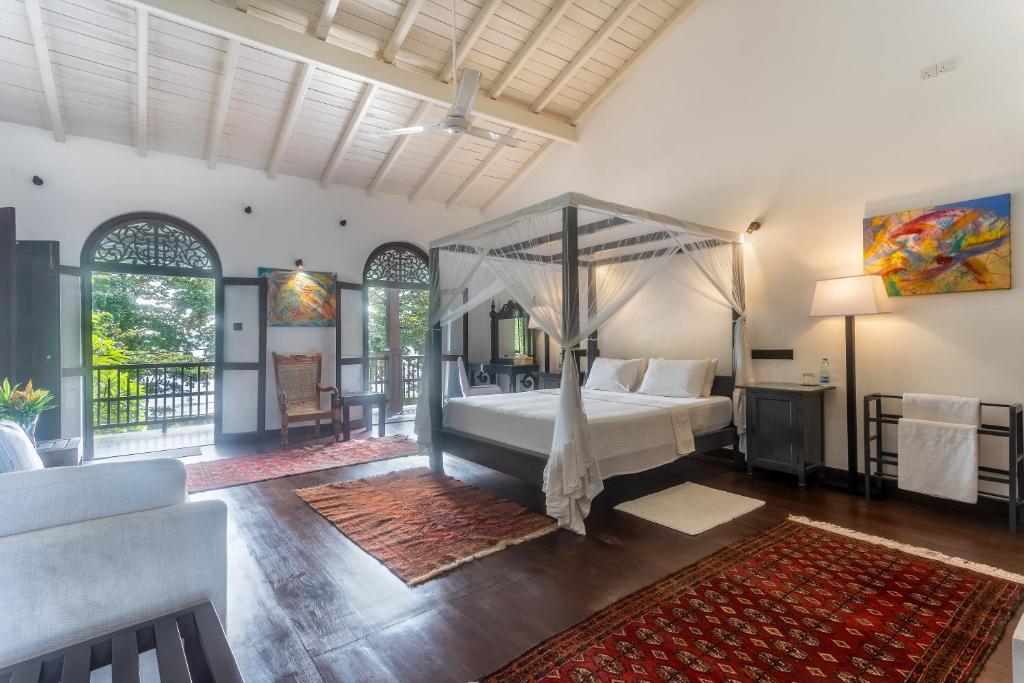 a bedroom with a canopy bed and a living room at Villa Aurora, Galle Fort in Galle