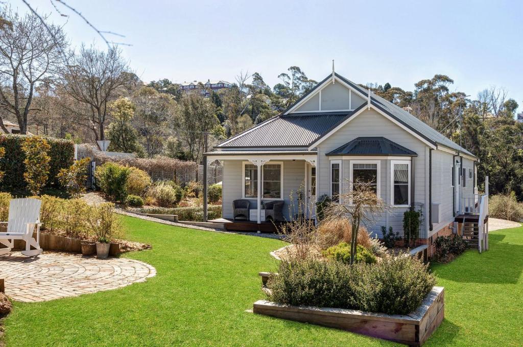 una pequeña casa blanca con jardín en un patio en Cumberland House, en Katoomba