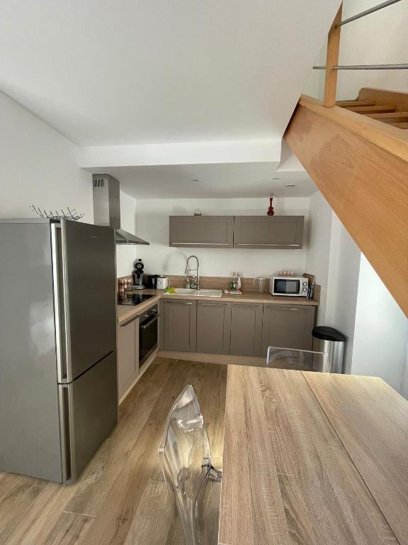 a kitchen with a stainless steel refrigerator and a wooden table at Duplex en plein centre in Propriano