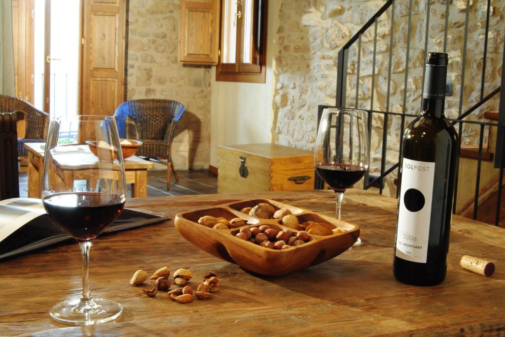 una botella de vino y un tazón de nueces en una mesa en Cal Porxo del Priorat en Pradell