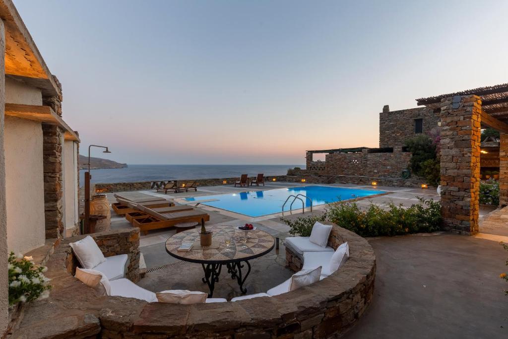 un patio con mesa y sillas junto a una piscina en Villa Myrto, breathtaking Aegean view, 5' from Koundouros beach, en Koundouros