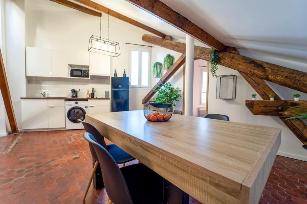 uma grande cozinha com uma mesa de madeira e cadeiras em Authentique studio hypercentre - clim - wifi em Nîmes