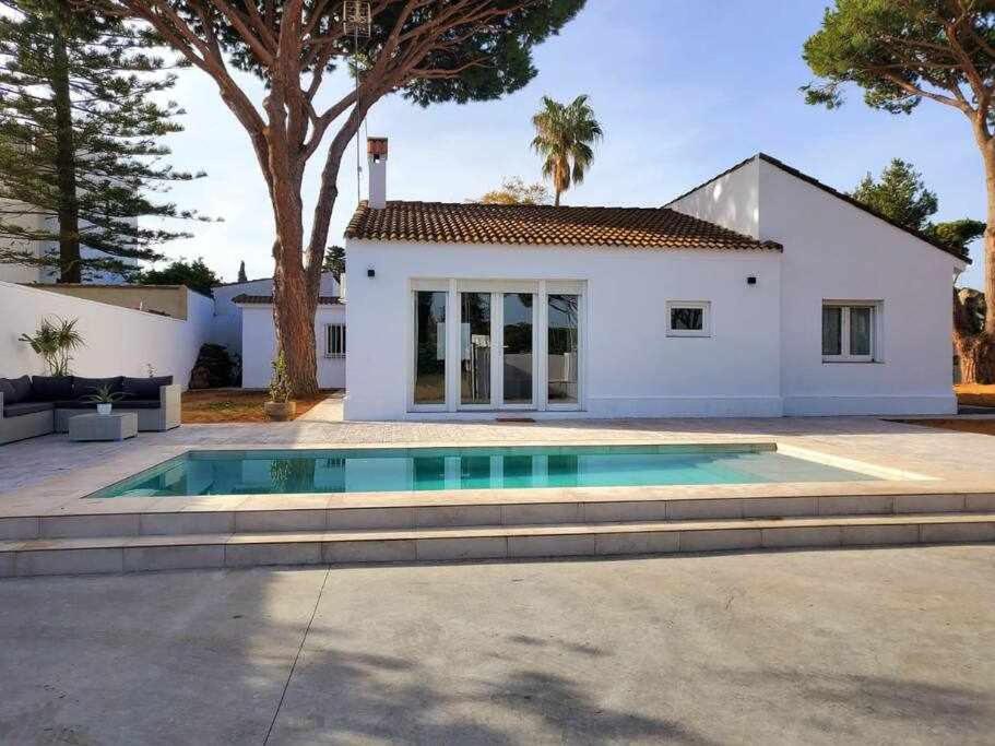 a house with a swimming pool in front of a house at Villa yoli 26 chalet con piscina cerca de la playa in Chiclana de la Frontera