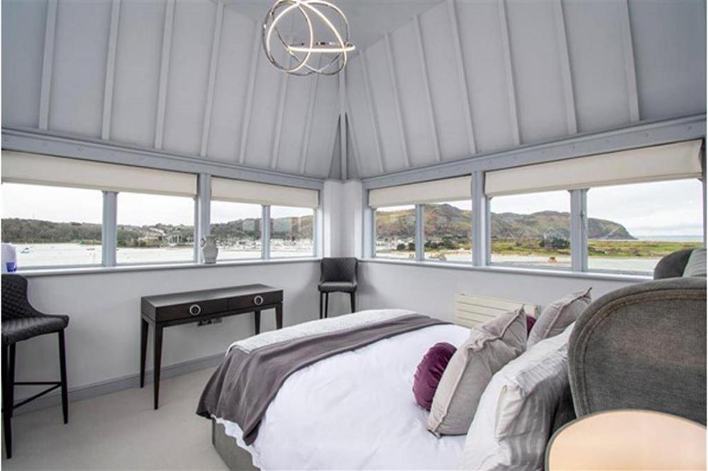 a bedroom with a bed and some windows at Deganwy Tower Apartment in Deganwy
