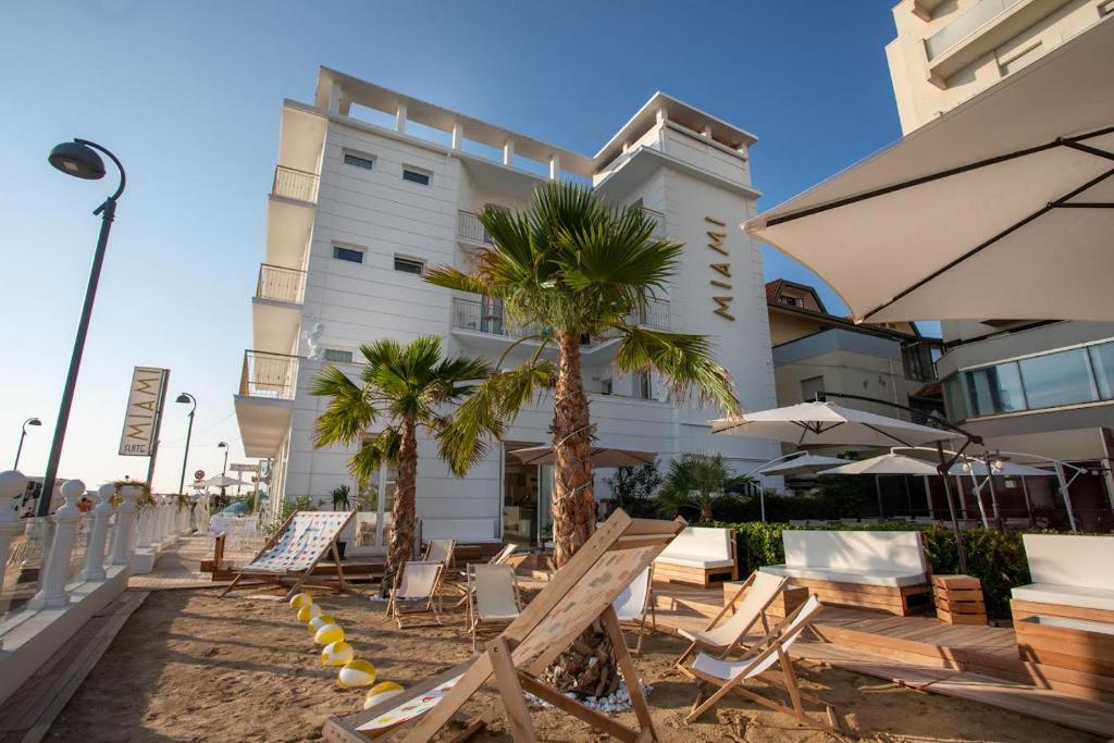 a hotel with chairs and palm trees in front of a building at Miami Suite in Bellaria-Igea Marina