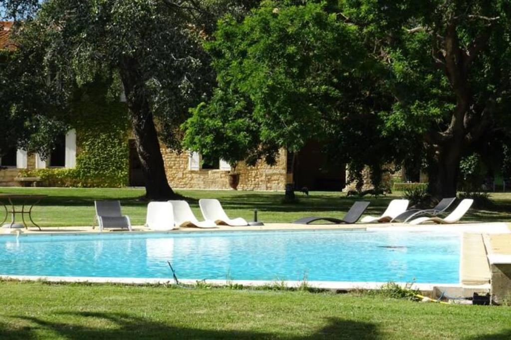 a group of lounge chairs by a swimming pool at Les Jasmins 8 pers Piscine commune calme et confort in Saint-Gilles