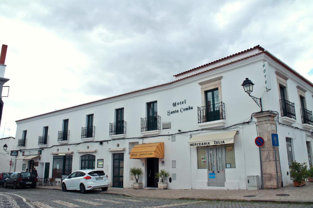 a white building with a car parked in front of it at Hotel Santa Comba in Moura