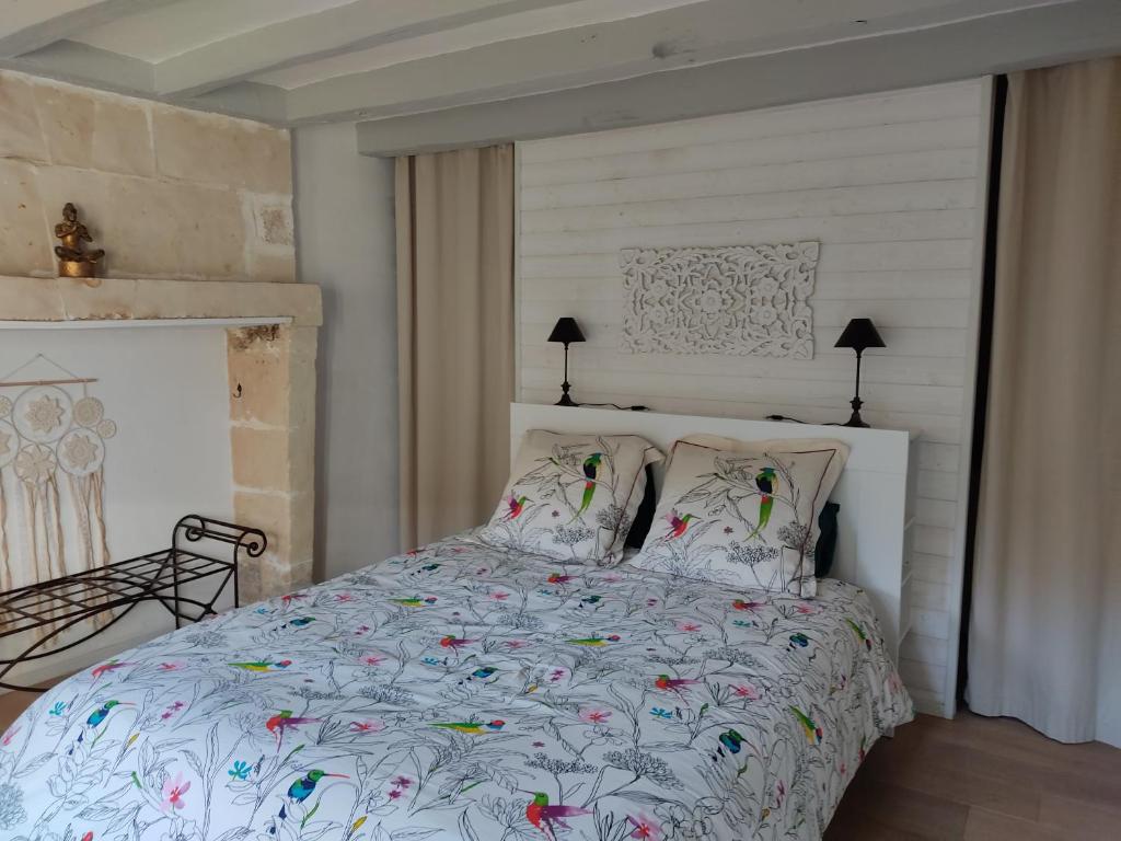 una camera da letto con un letto con copriletto floreale di Au Jardin de la Marquetterie a Cigogné