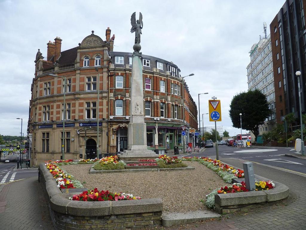 a building with a statue and flowers in front of it at 5- bed gem in Barnet short let luxury awaits in Barnet