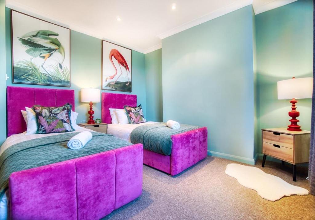 two beds in a room with pink furniture at Dorset Green Two By My Getaways in Brighton & Hove