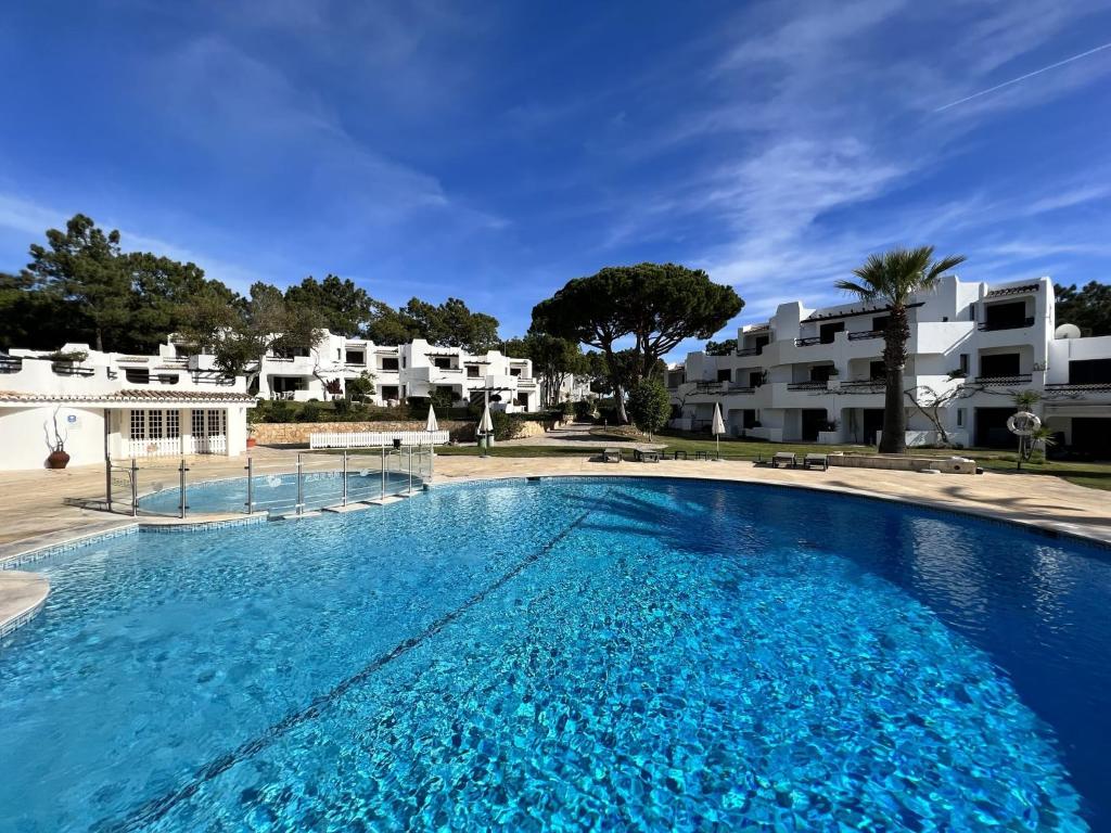 een groot blauw zwembad met gebouwen op de achtergrond bij Albufeira Balaia Golf Village 1 With Pool by Homing in Albufeira