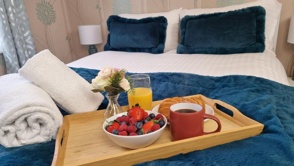 a tray with a plate of fruit on a bed at The Pearl of Greenwich - Two bedroom flat next to Cutty Sark in London
