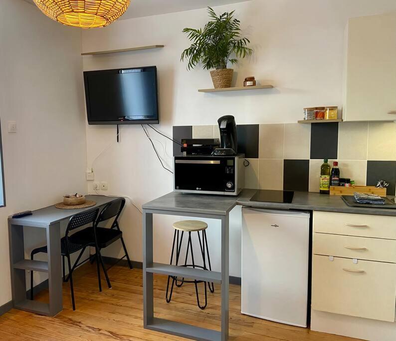 a kitchen with a counter and a tv on the wall at Studio Coquet proche Gare in Bourg-en-Bresse