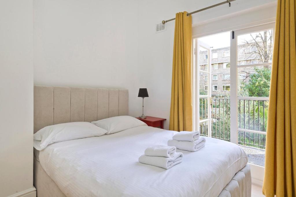 una camera da letto con un letto bianco e asciugamani di Bright one bedroom apartment with balcony in Maida Vale by UnderTheDoormat a Londra