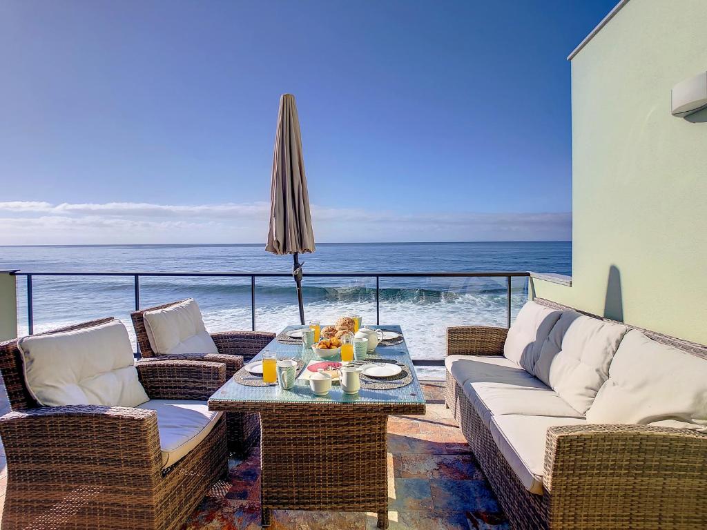 um pátio com uma mesa e cadeiras e o oceano em On the Wave by LovelyStay em Paul do Mar