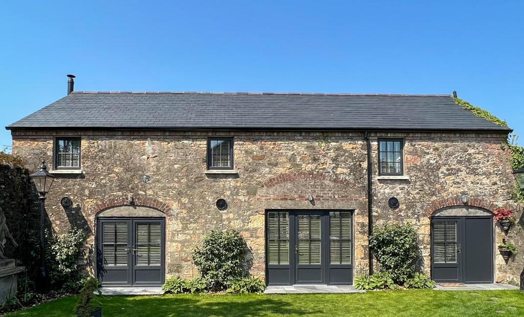 a large brick house with two garage doors at Converted Victorian Coach House with Hot Tub in Stewartstown