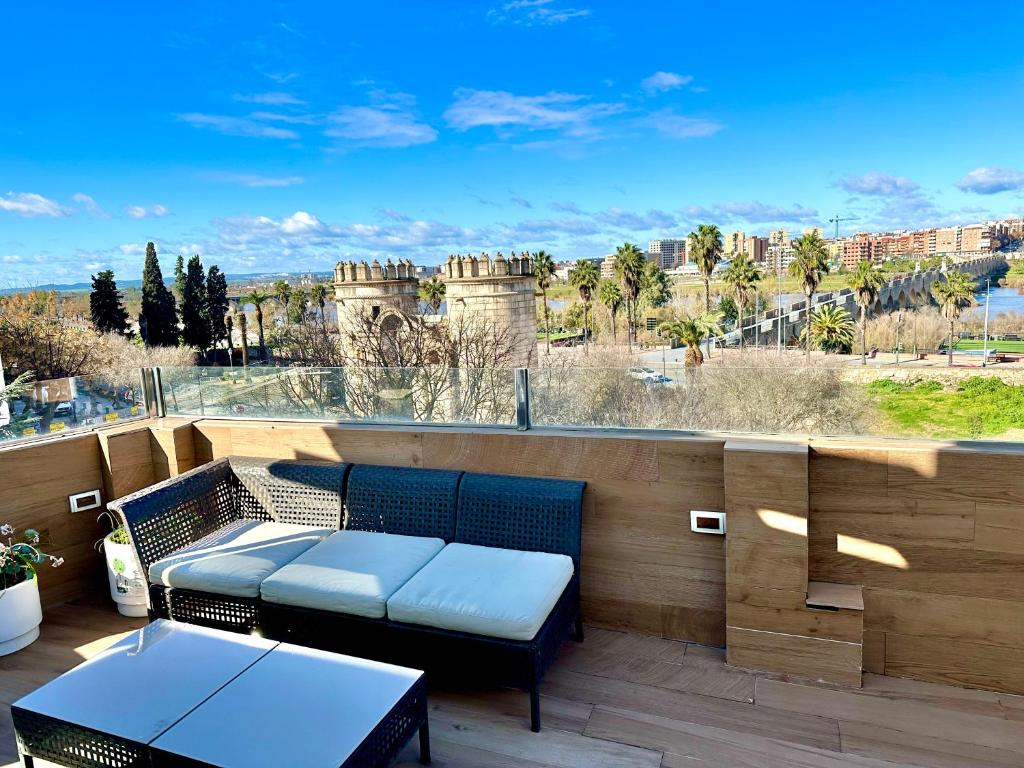 a patio with a table and benches on a balcony at Alojamientos Puerta Palma con vistas y Parking in Badajoz