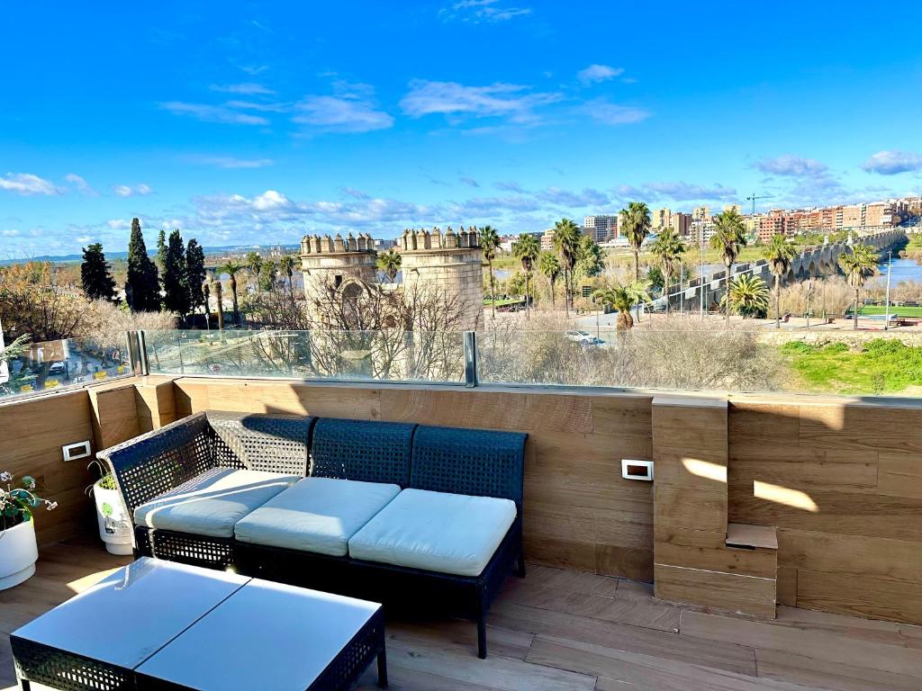 eine Terrasse mit einem Tisch und Bänken auf einem Balkon in der Unterkunft Puerta Palma con vistas únicas y aparcamiento in Badajoz