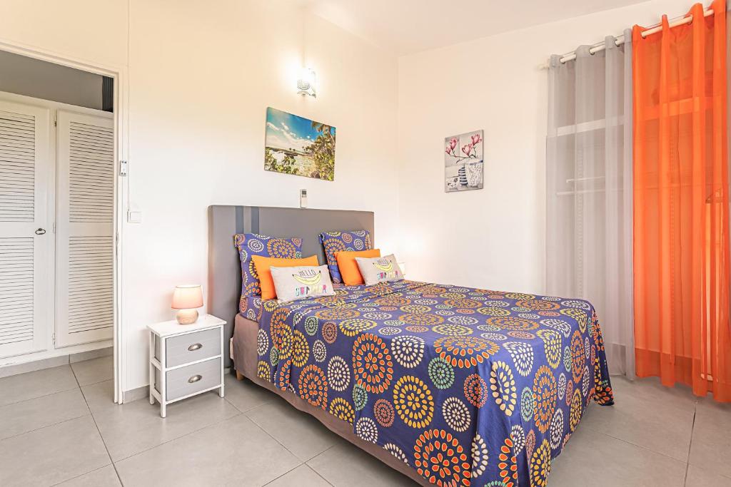 a bedroom with a bed with a colorful comforter at Villa de 3 chambres avec piscine privee jacuzzi et jardin clos a Baie Mahault in Baie-Mahault