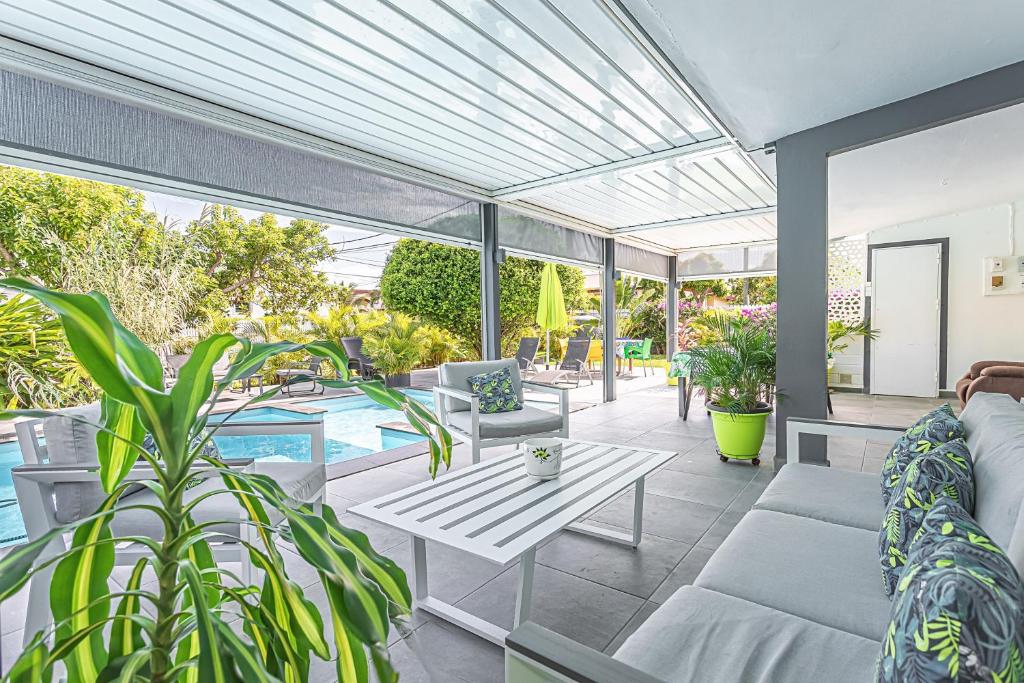 a patio with a couch and a table and a pool at Villa de 3 chambres avec piscine privee jacuzzi et jardin clos a Baie Mahault in Baie-Mahault