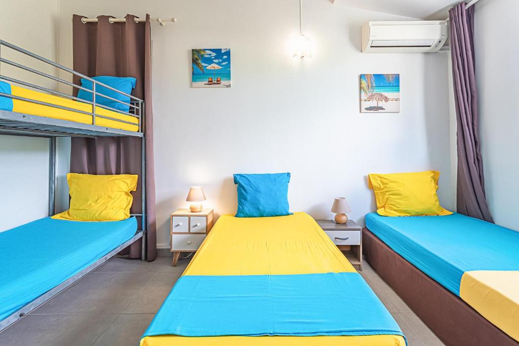 two beds in a room with a bunk bed at Villa de 3 chambres avec piscine privee jacuzzi et jardin clos a Baie Mahault in Baie-Mahault