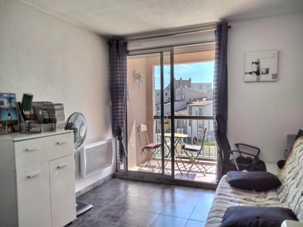 a living room with a couch and a balcony at Studio Port du Cap d'Agde in Cap d'Agde