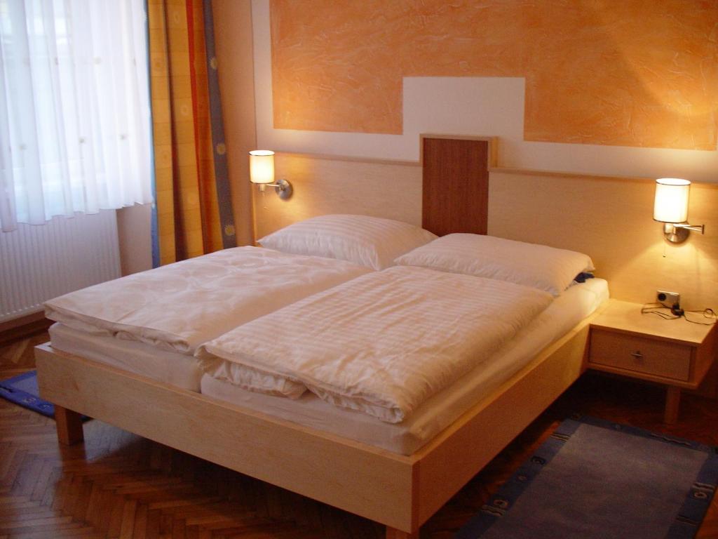 a bed in a bedroom with two lamps on a table at Gasthof Schwabl Wirt in Vienna