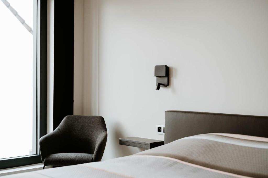 - une chambre avec un lit et une chaise à côté d'une fenêtre dans l'établissement B&B Koor91, à Hasselt