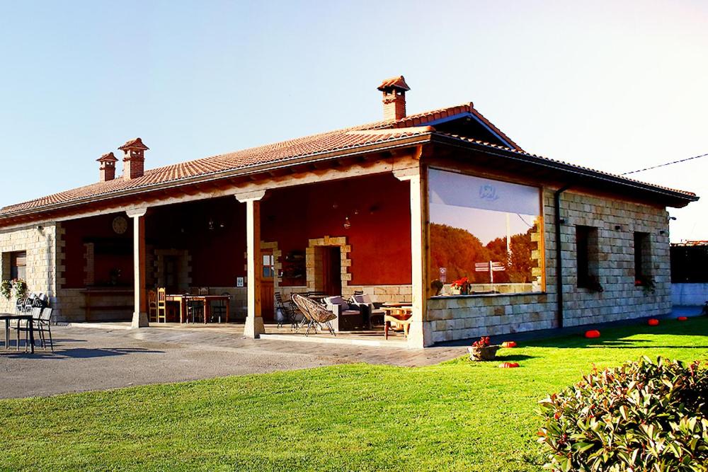 una casa con una gran ventana en la parte delantera en La Cala Hostel en Loredo