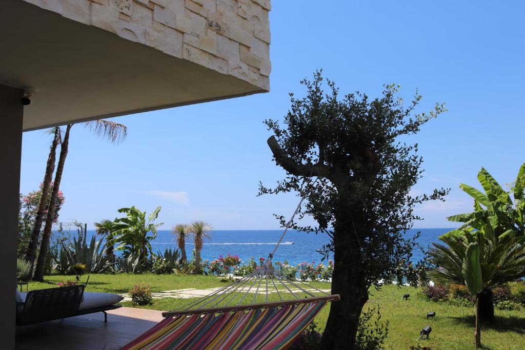 een hangmat op een terras met de oceaan op de achtergrond bij Vesper Suites in Dhërmi