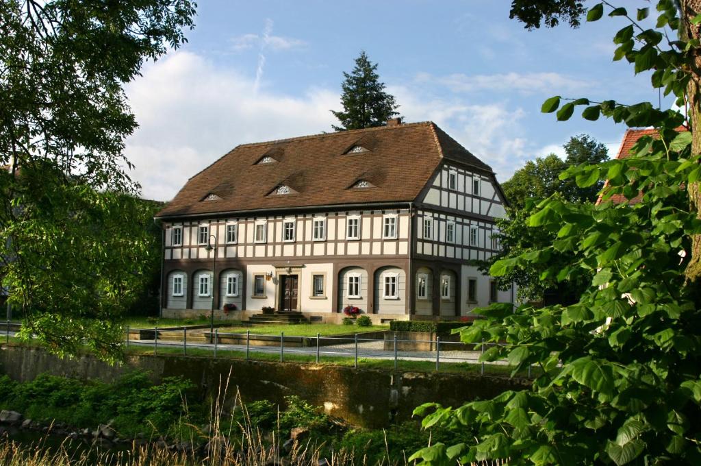 un gran edificio blanco con techo marrón en Komfort-Ferienwohnung "Zur Schmiedebrücke" en Großschönau