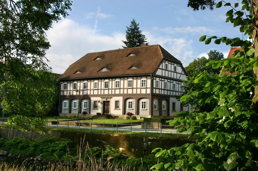 um grande edifício branco com um telhado castanho em Komfort-Ferienwohnung "Zur Schmiedebrücke" em Grosschönau