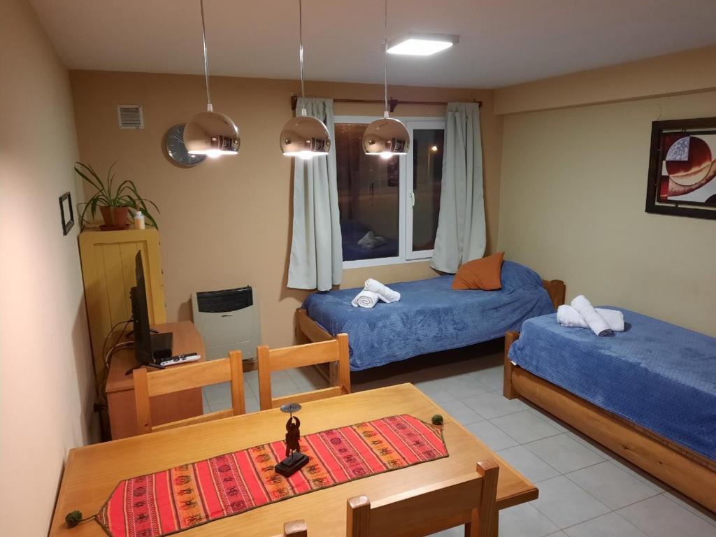 Sala de estar con 2 camas y mesa en Portal Sureño en Dina Huapi