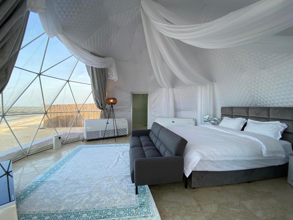 a bedroom with a bed and a couch and a large window at Turquoise Resorts in Ruwais