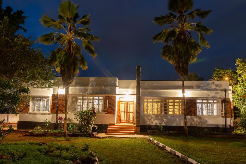 a white house with palm trees in front of it at MUTIMA VILLA in Jinja