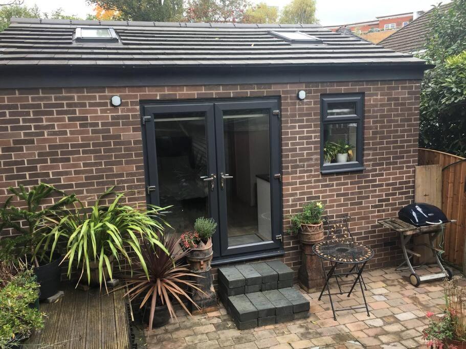 una casa di mattoni con una porta nera e alcune piante di Beautiful detached private annex in great location a Manchester