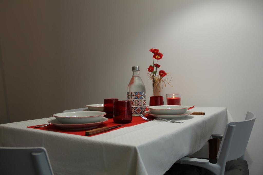 una mesa con un mantel y platos blancos y una botella en The Blue Nest - Red Apartment near 5 Terre en La Spezia