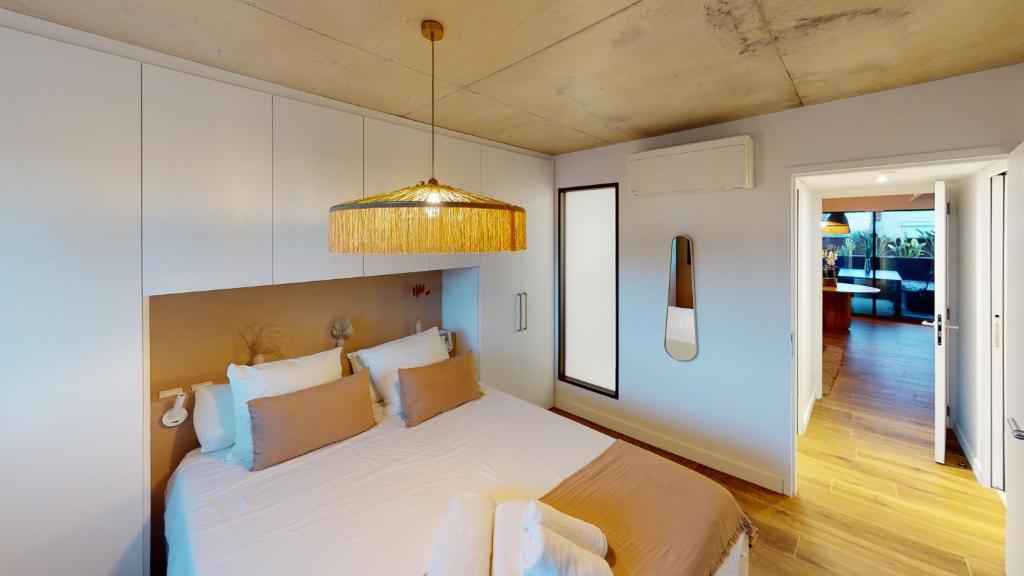 sypialnia z dużym białym łóżkiem i żyrandolem w obiekcie Villa Ananda - Chandra - Un havre de paix entre mer et étangs w mieście Carnon-Plage