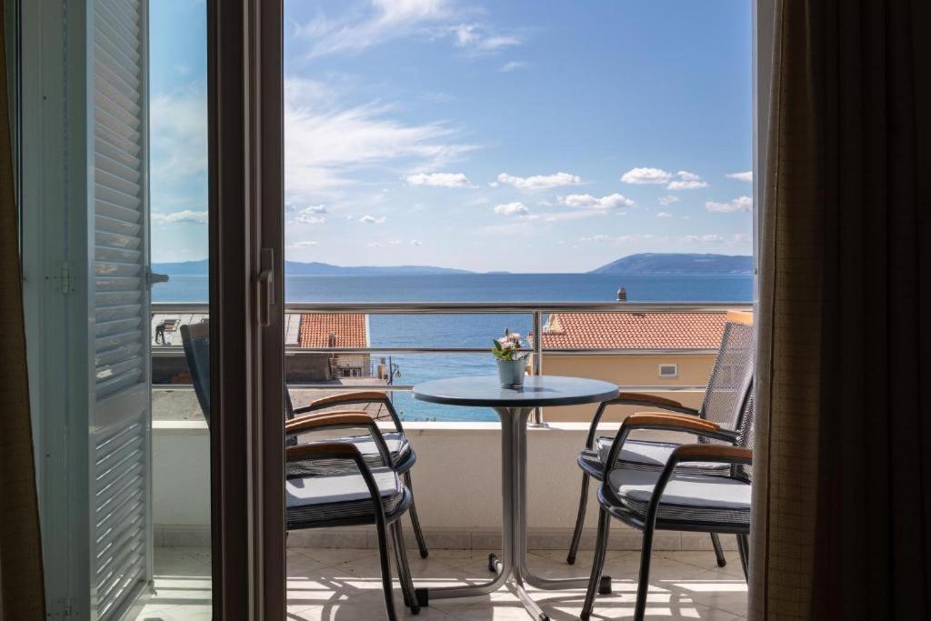 een balkon met een tafel en stoelen en uitzicht op de oceaan bij Apartmani Vela in Tučepi