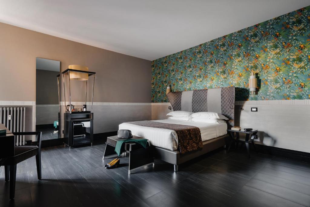 1 dormitorio con 1 cama y papel pintado con motivos florales en Unica Suites Rome en Roma