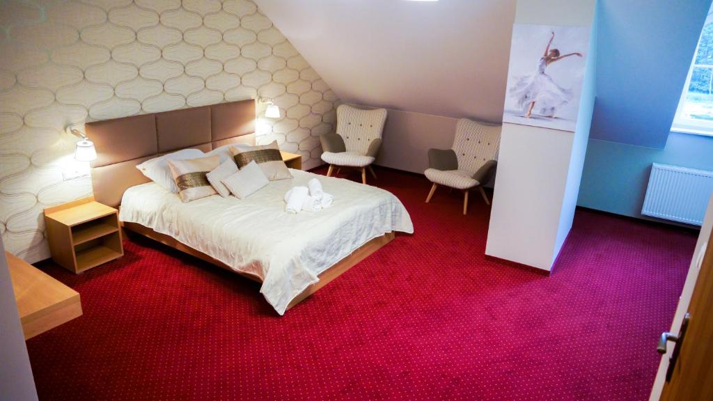 a bedroom with a large bed with a red carpet at Szafranowy Dwór in Strawczyn