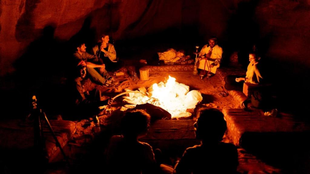 Eine Gruppe von Menschen, die um ein Feuer herum sitzen in der Unterkunft Magic Bedouin Night in Wadi Rum