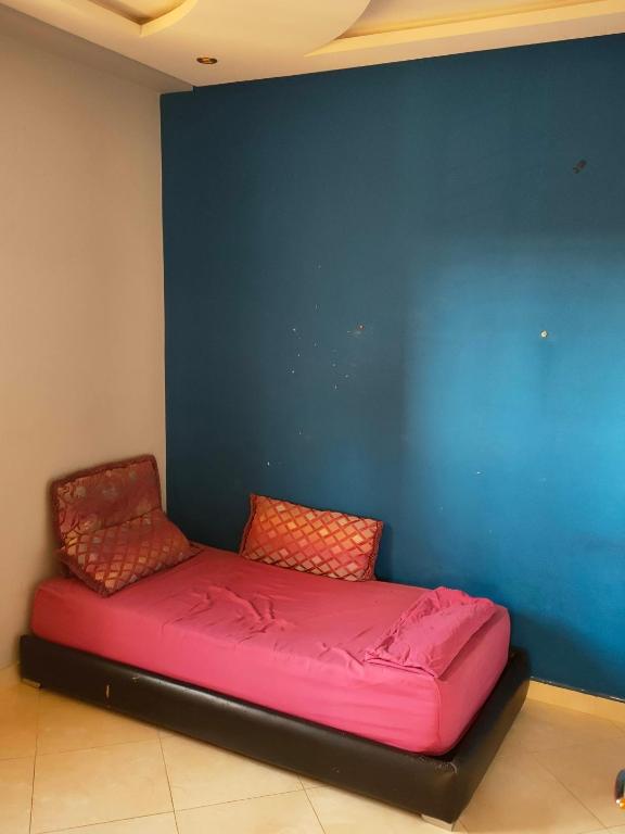 a red bed in a room with a blue wall at Appartement wifaq in Temara