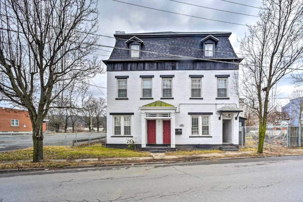 una casa blanca con una puerta roja en una calle en Troy Townhome 10 Mi to Downtown Albany!, en Troy