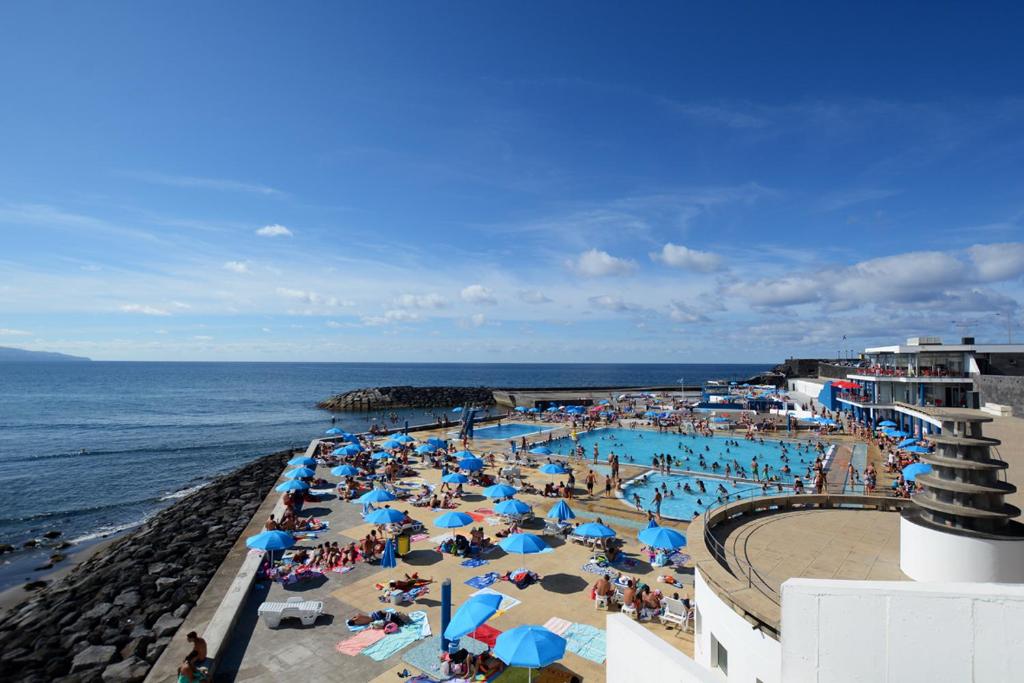 een groep mensen op een strand met een zwembad bij Mojo House in Ribeira Grande