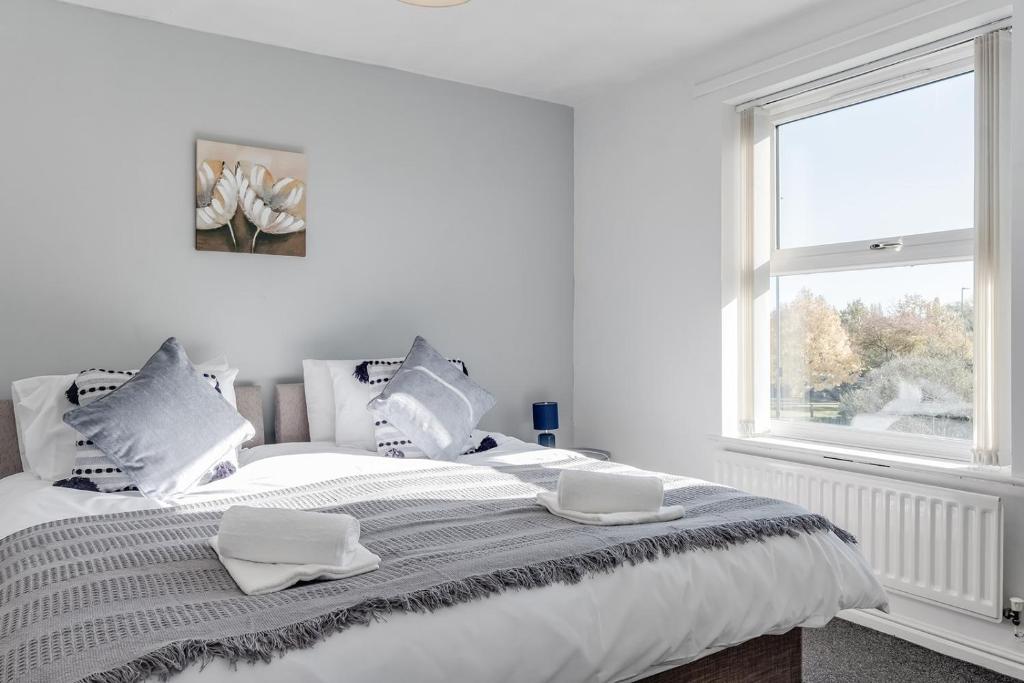 um quarto branco com uma cama com duas toalhas em Spacious and Comfortable Home near Fosse Park em Kirby Muxloe