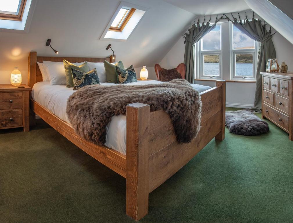 a bedroom with a large bed with a cat laying on it at The Lodge in the Loch in Portree